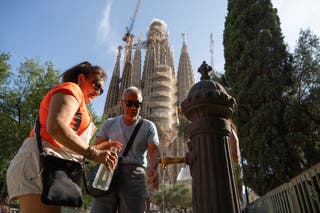 مردم بطری های خود را در یک چشمه عمومی در مقابل باسیلیکای Sagrada Familia در بارسلونا دوباره پر می کنند